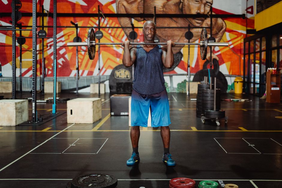 Muscular man lifting barbell in a colorful gym, exuding strength and fitness.
