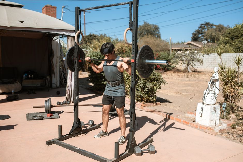 Man doing a barbell squat in an outdoor gym setting for strength training.